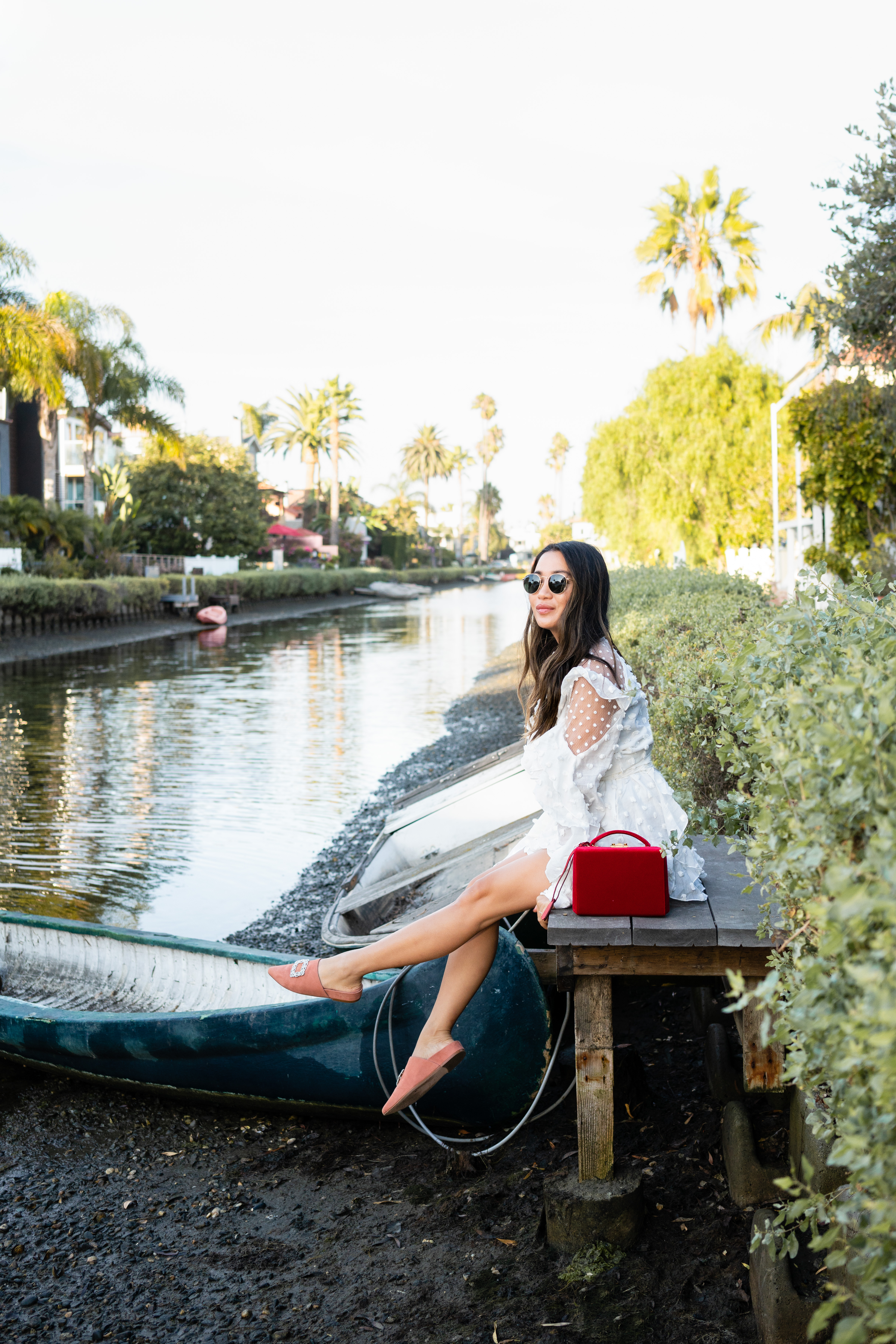 Venice Canals at Venice Beach wearing white polka dot romper and Stuart Weitzman mules and Mark Cross grace bag