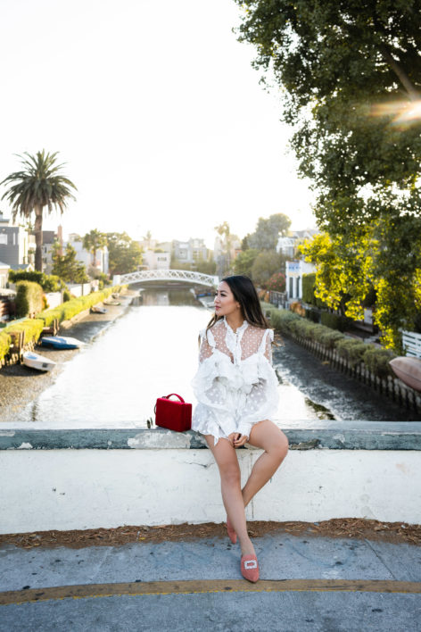 Venice Canals at Venice Beach in polka dot romper outfit and Stuart Weitzman mules and Mark Cross grace bag